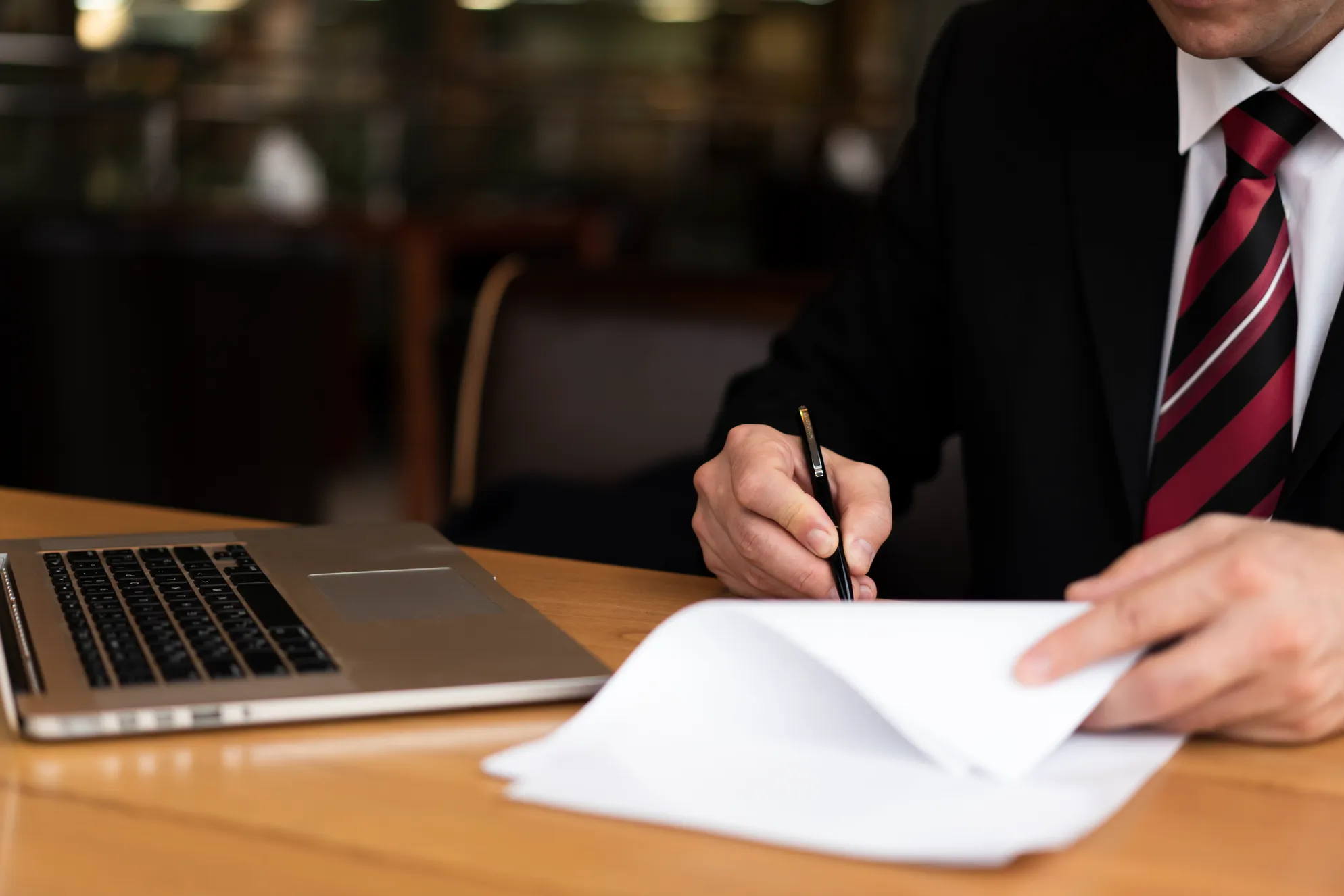 La firma de documentos oficiales representa una etapa esencial dentro de los servicios legales que garantizan validez jurídica. Una persona firma un contrato en el escritorio como parte de los procesos incluidos en los servicios legales.