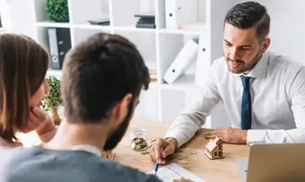 Un hombre de camisa blanca y corbata explicando a una pareja en que consiste la administración de condominios CDMX.